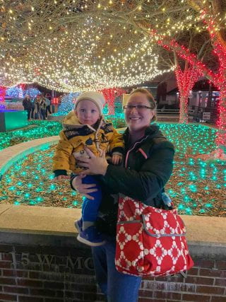 Katherine and child in front of Christmas lights
